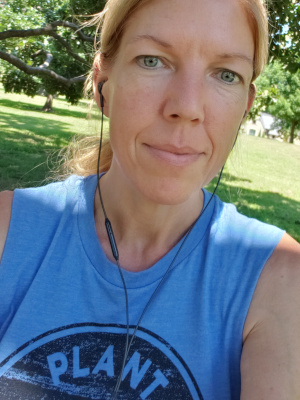 Beth walking in nature, plant power shirt on from VegFest